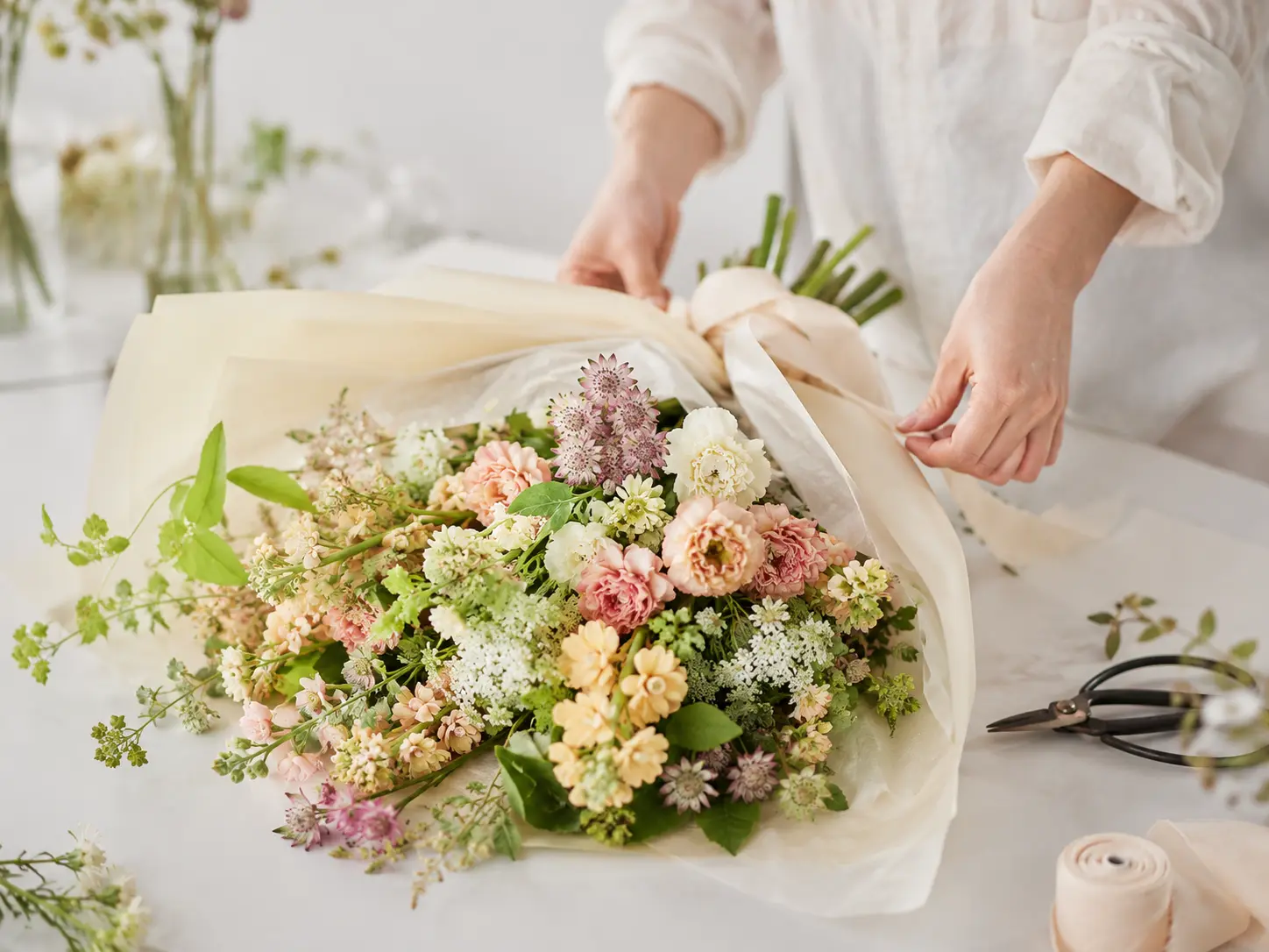 花束を丁寧に包むフローリストの手元
